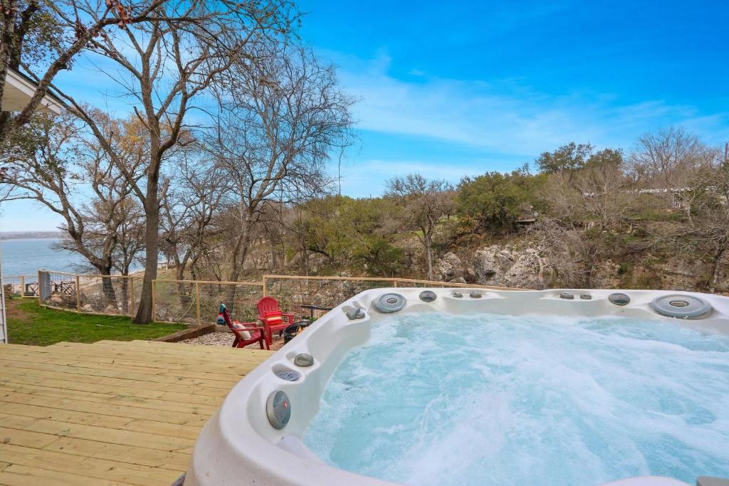 einen Whirlpool auf einer Terrasse mit Blick auf das Wasser in der Unterkunft Baby Owl Lakehouse in Canyon Lake