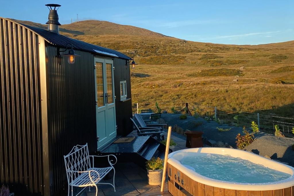 a house with a jacuzzi tub on a patio at Slieve Croob Glamping in Ballyward