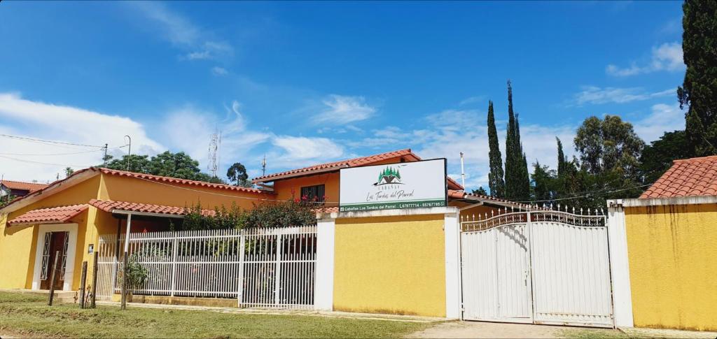 una casa amarilla con una valla blanca y una señal en Los Tordos del Parral, en Samaipata