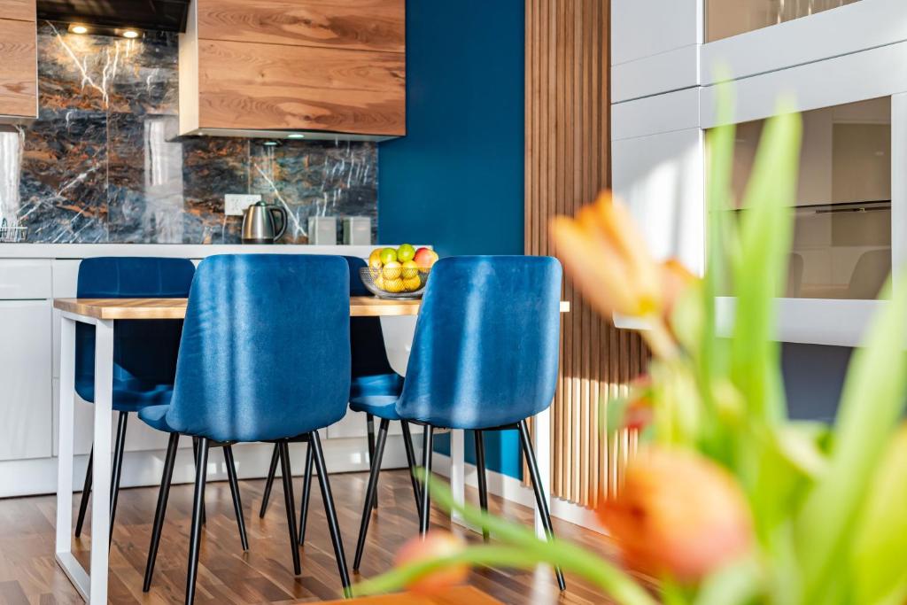 kuchnia z niebieskimi krzesłami i drewnianym stołem w obiekcie Villa Garden Żołnierska w Olsztynie
