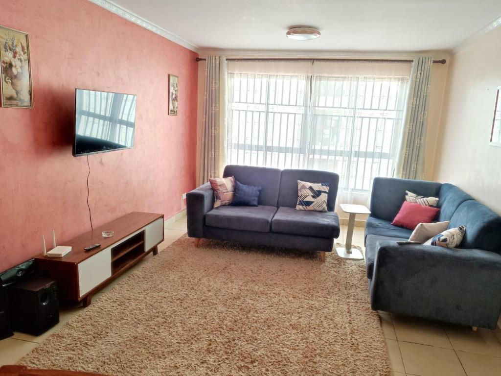 sala de estar con 2 sofás azules y TV en 3Bedroom Greatwall Gardens Mombasa Rd NBO, en MakandaraHousing Estate