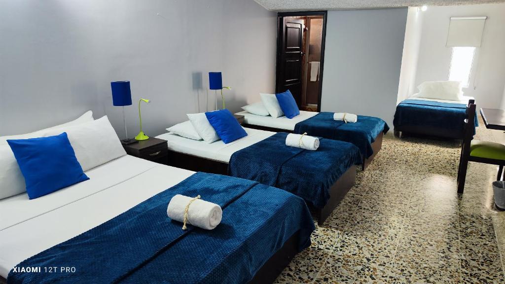 a hotel room with three beds with blue sheets at Hotel Loft Dorado in Floridablanca
