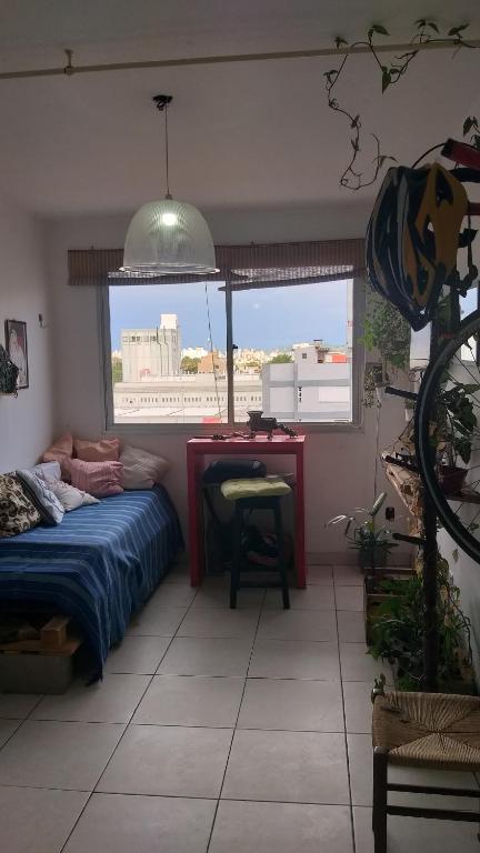 a bedroom with a bed and a desk and a window at Apto do Thiago e da Chori in Porto Alegre