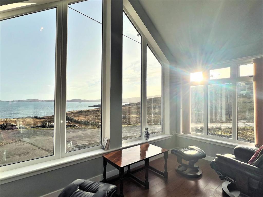 a living room with windows with a view of the ocean at Jayne Cottage in Tarbert