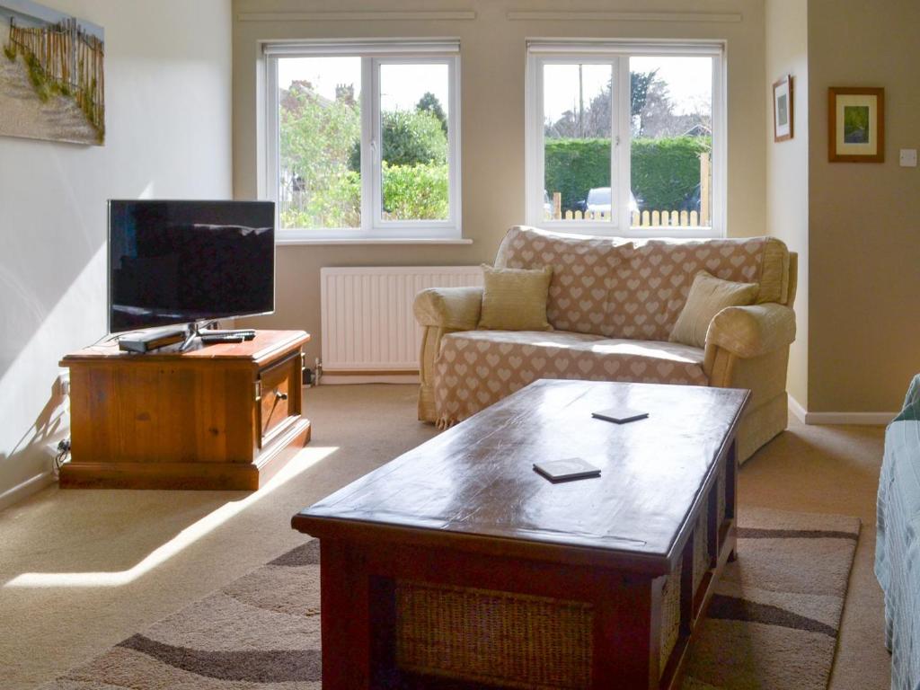 a living room with a couch and a tv at Beach House in Sheringham