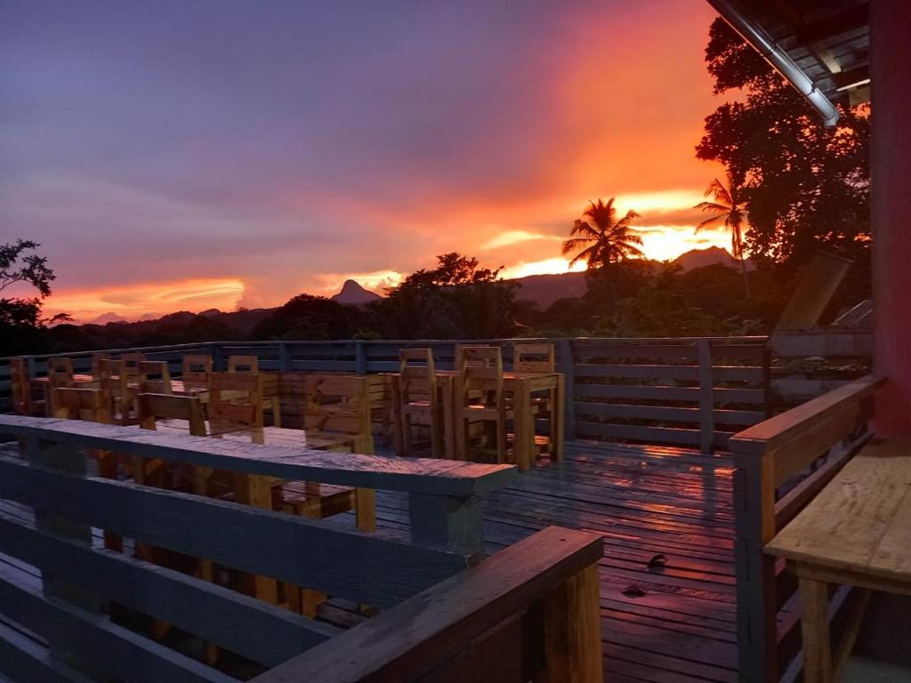 a deck with tables and chairs and a sunset at Casa Cantagalo - Guest House & Bar Restaurant in Santana