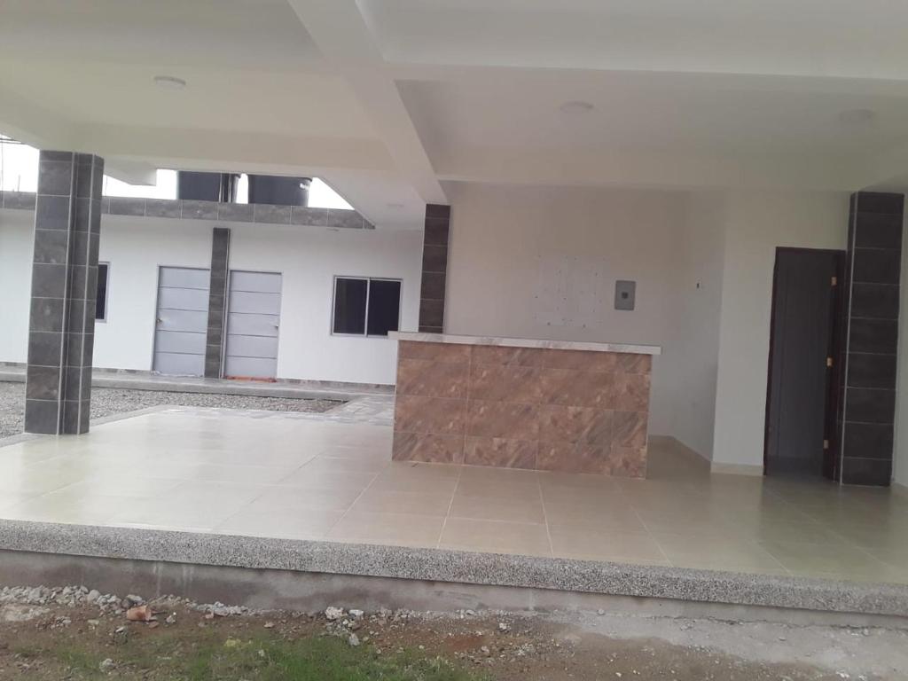 Habitación grande y vacía con paredes blancas y pared de madera. en HOSTAL KASHI KAI en San Juan del Cesar