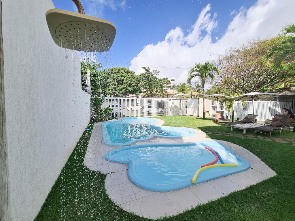 a swimming pool in a backyard with a sprinkler at Pousada Praia do Flamengo Suítes in Salvador