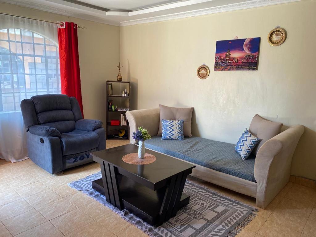 ein Wohnzimmer mit einem Sofa, einem Stuhl und einem Tisch in der Unterkunft Razy's in Kakamega