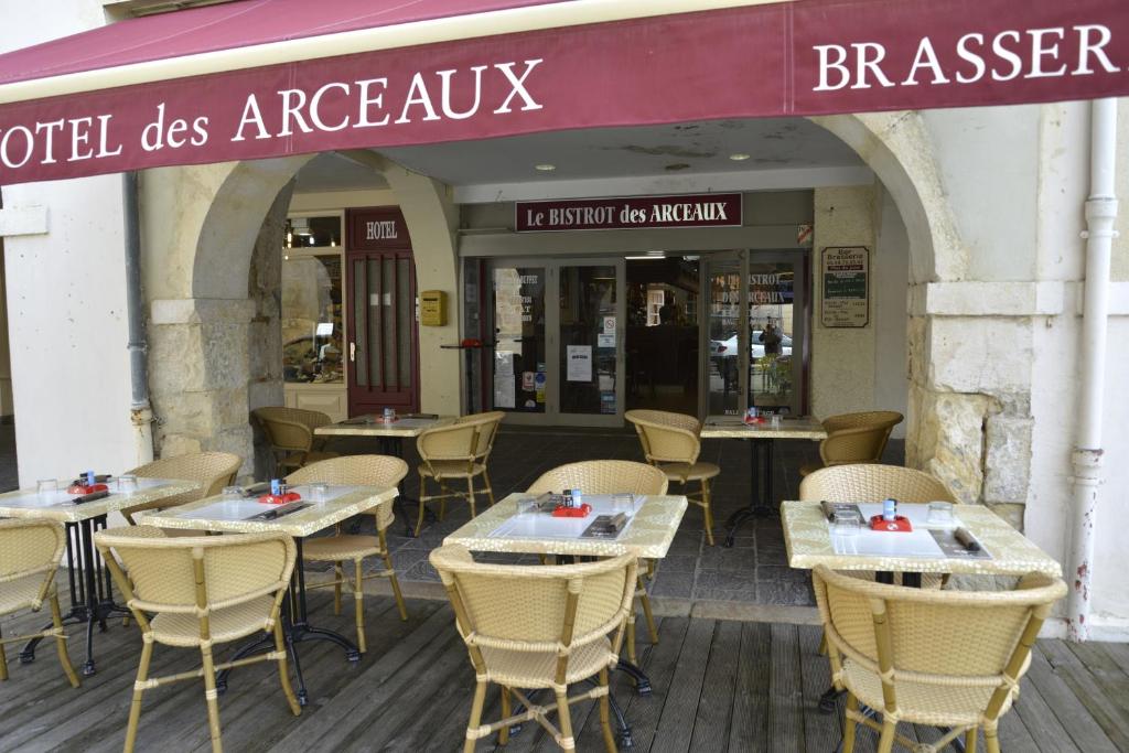 a restaurant with tables and chairs in front of a building at Hôtel Des Arceaux in Saint-Sever