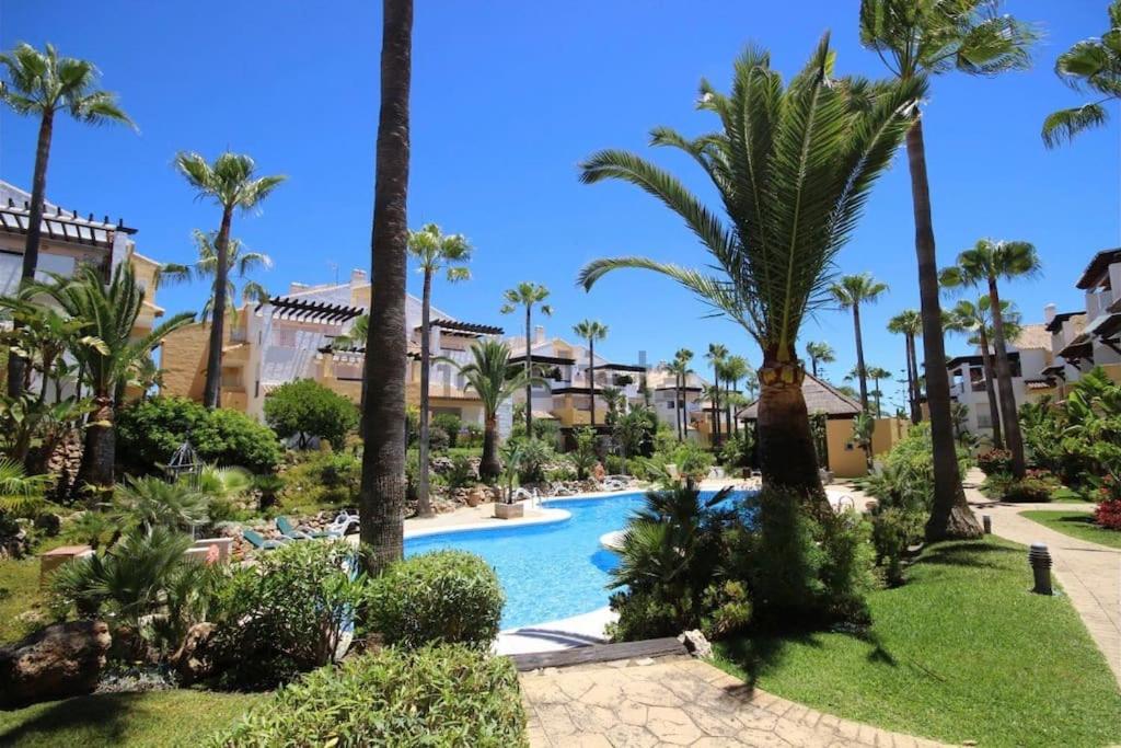 una piscina in un resort con palme di Apartamento en primera línea de playa a Marbella