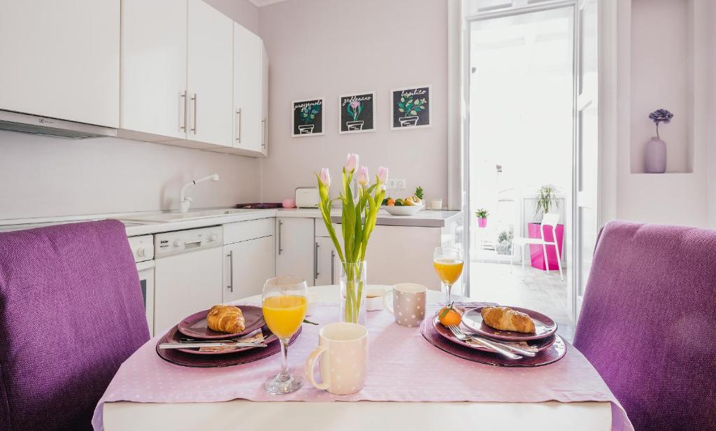 una mesa con platos de comida y dos vasos de zumo de naranja en Apartment for special getaway Nea en Pula