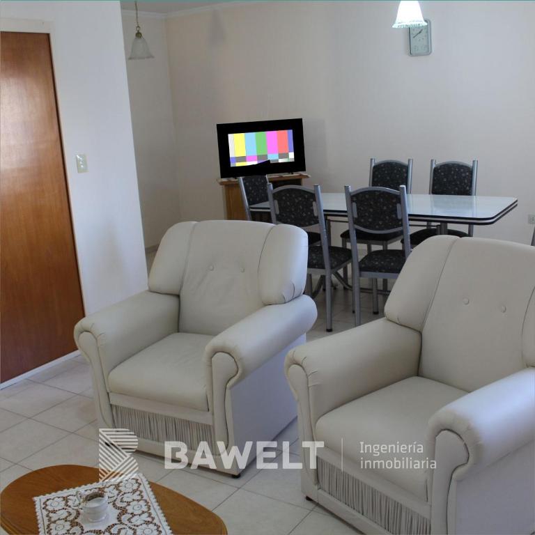 sala de estar con 2 sillas blancas y mesa en Marianella Apart Familiar en Río Cuarto