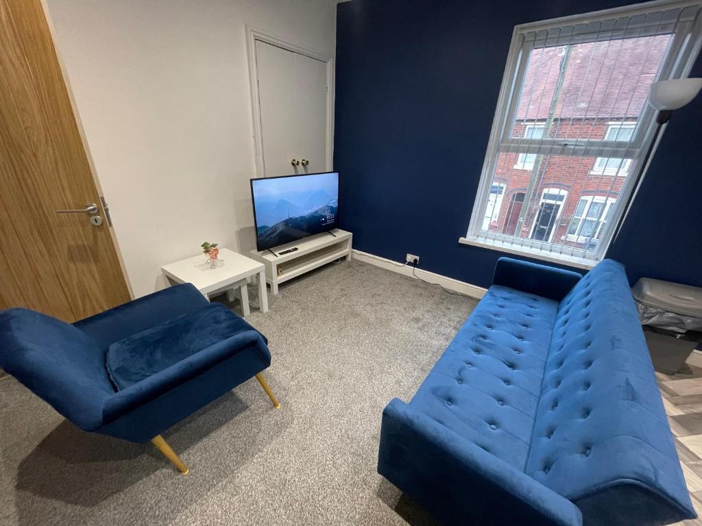 a living room with a blue couch and a tv at Modern Spacious 2 Bedroom Apt in Rowley Regis