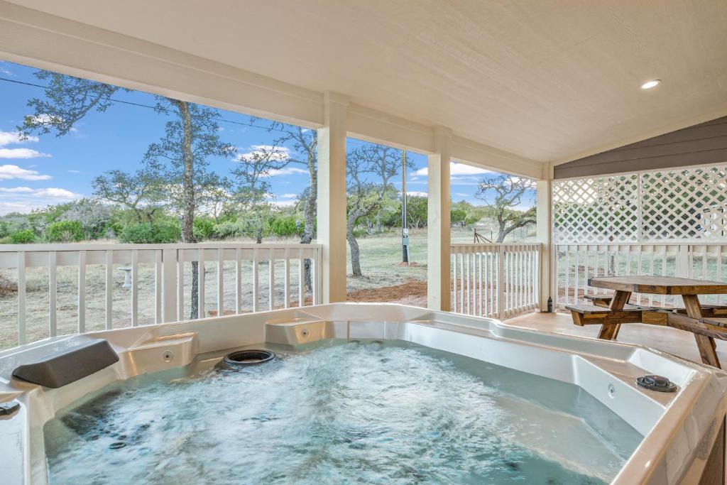 a jacuzzi tub in a porch with a table and a picnic table at Appian Way Maltese Cottage in Fredericksburg