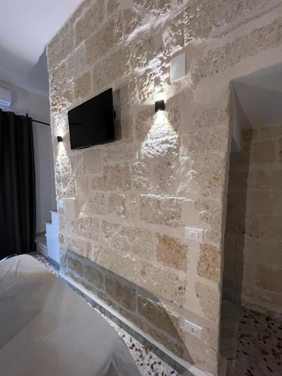 Habitación con pared de piedra y TV. en La PortaVecchia - #Home, en Monopoli