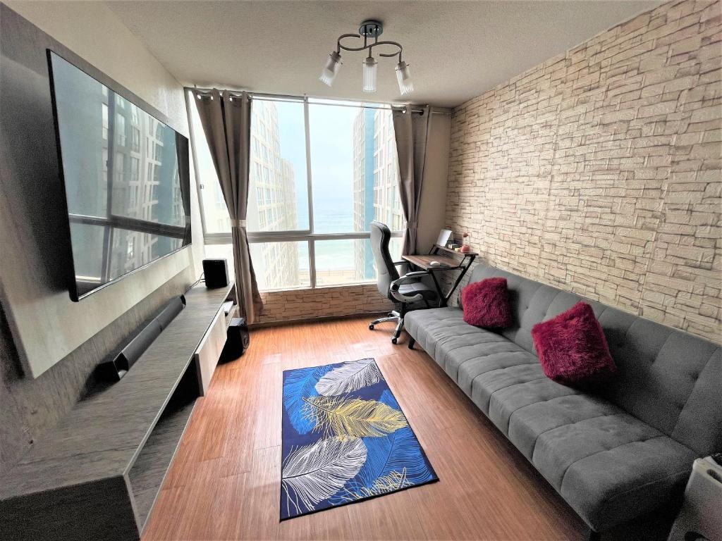 sala de estar con sofá y ventana grande en Departamento entero super cómodo Airi House N3, en Lima