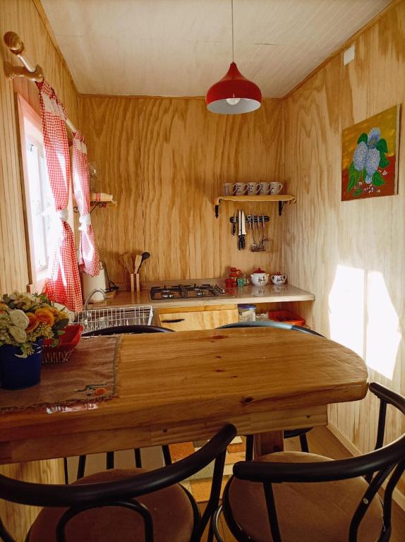 a kitchen with a wooden table and two chairs at Cabañas Aulen Chepu Chiloe in Ancud