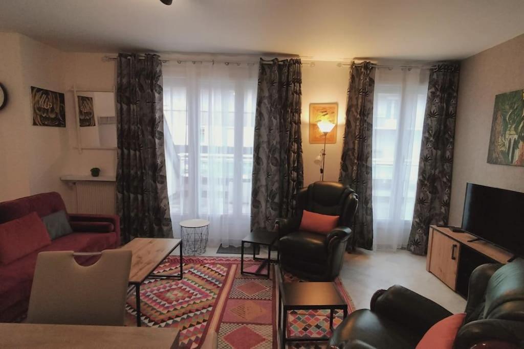 a living room with a couch and chairs and a television at Spacious flat close to the railway station in Troyes