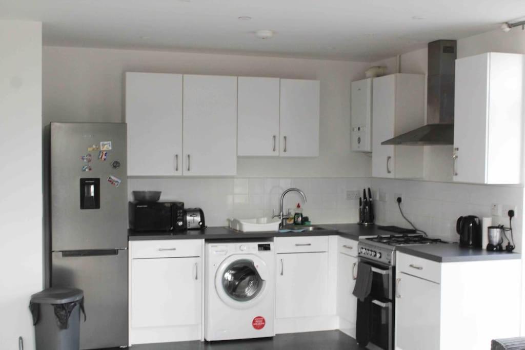 a kitchen with white cabinets and a washing machine at Lovely one bedroom apartment with balcony in Forest Hill