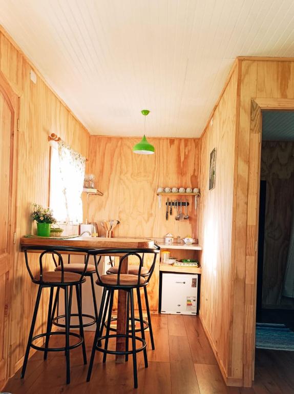 a kitchen with wooden walls and a table and stools at Cabañas Aulen Chepu Chiloe in Ancud