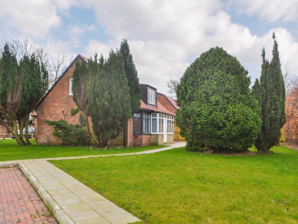 a brick house with trees in front of it at Forest Close in Forest Hall