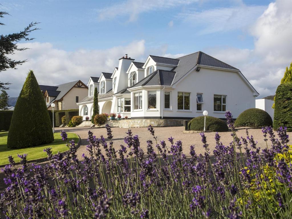 a white house with purple flowers in front of it at Arches Country House in Donegal