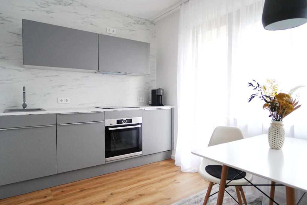 a white kitchen with a table and a counter top at Apartment mit Schwimmbad und Privatparkplatz in Augsburg