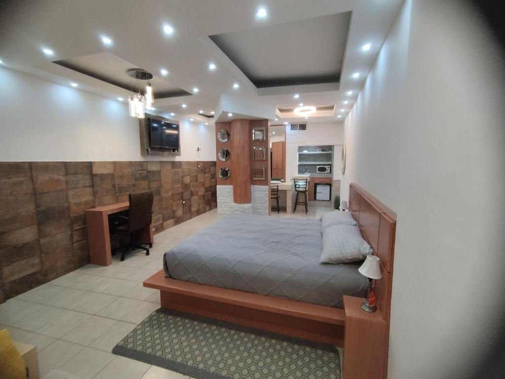 a bedroom with a bed and a desk and a kitchen at DEPARTAMENTO ALTOS 4 CERCA DEL CONSULADO in Ciudad Juárez