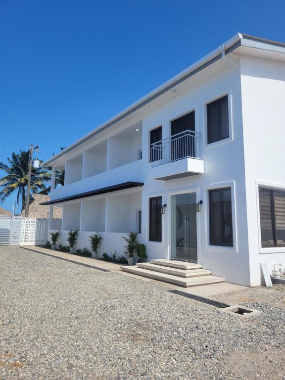 una casa blanca con una palmera en el fondo en Tramonto Boutique Hotel en La Ceiba