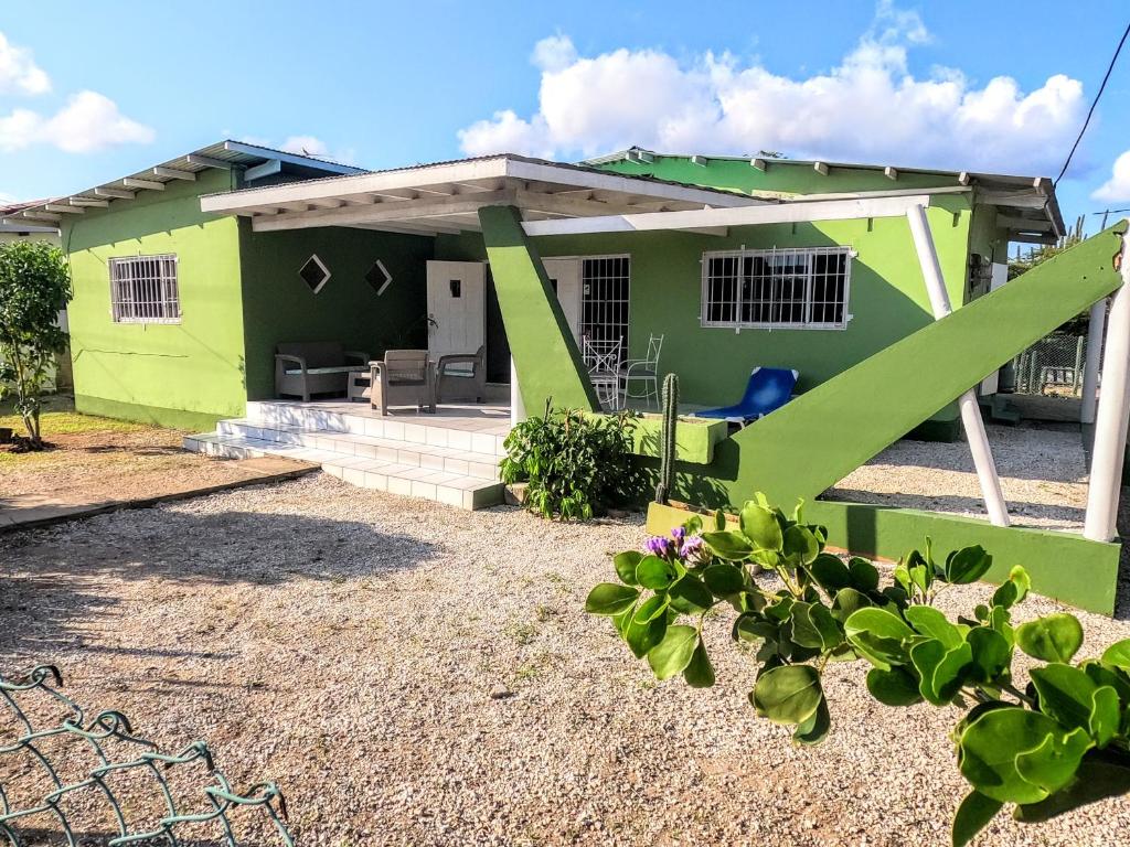 a green house with a patio in front of it at Traditional Aruban Home close to Surfside Beach in Oranjestad