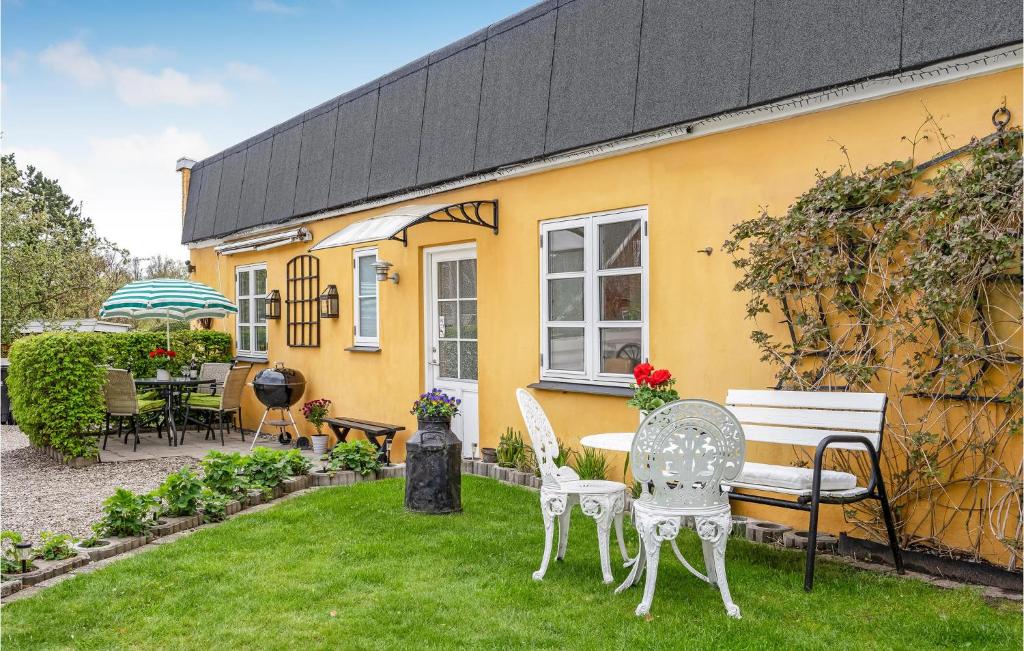 ein gelbes Haus mit Stühlen und einem Tisch im Hof in der Unterkunft Awesome Home In Hornbk With Kitchen in Hornbæk