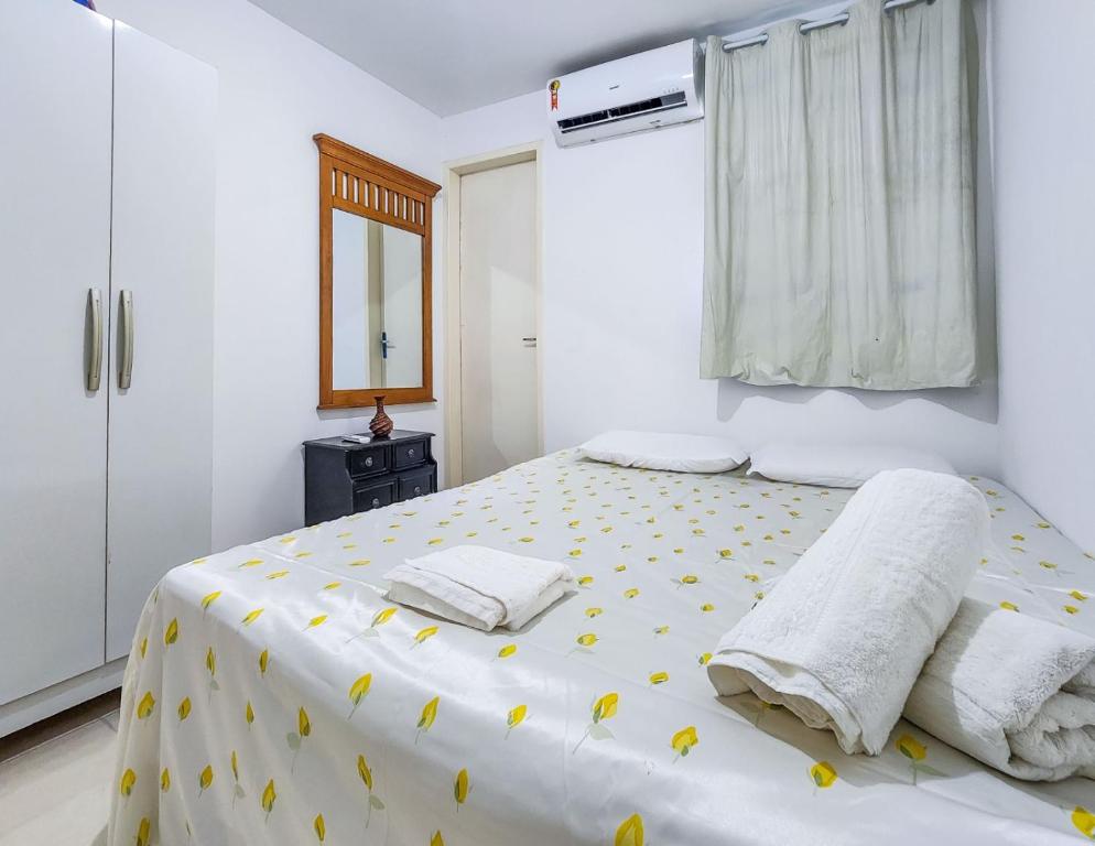 Apartamento Maria Farinha في ماريا فارينها: غرفة نوم بيضاء مع سرير مع ورود صفراء عليه