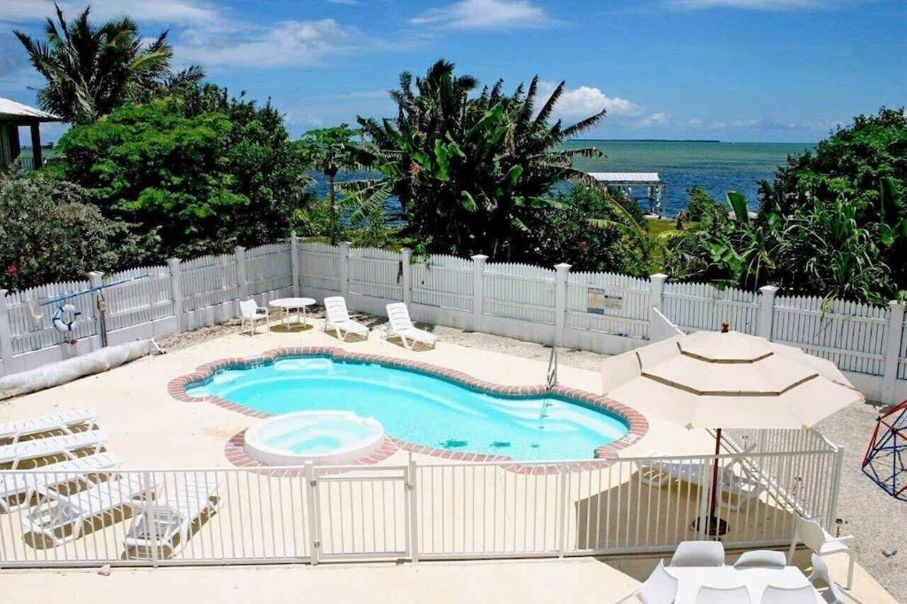 a pool with chairs and an umbrella and the ocean at Private Estate Pool Ocean View 20 minutes to Key West in Summerland Key
