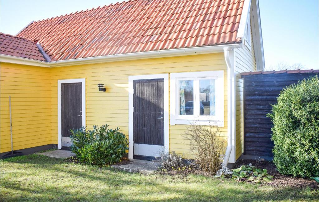 una casa gialla con tetto rosso di Beautiful Home In Frjestaden With Kitchen a Färjestaden