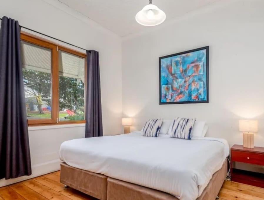 a bedroom with a large bed and a window at MèRose Place - Cottage on George in Bathurst