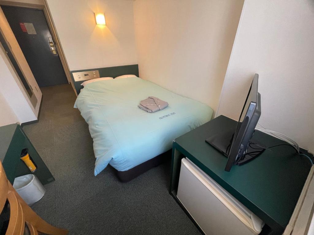mały pokój z łóżkiem i telewizorem w obiekcie Olympic Inn Azabu w Tokio