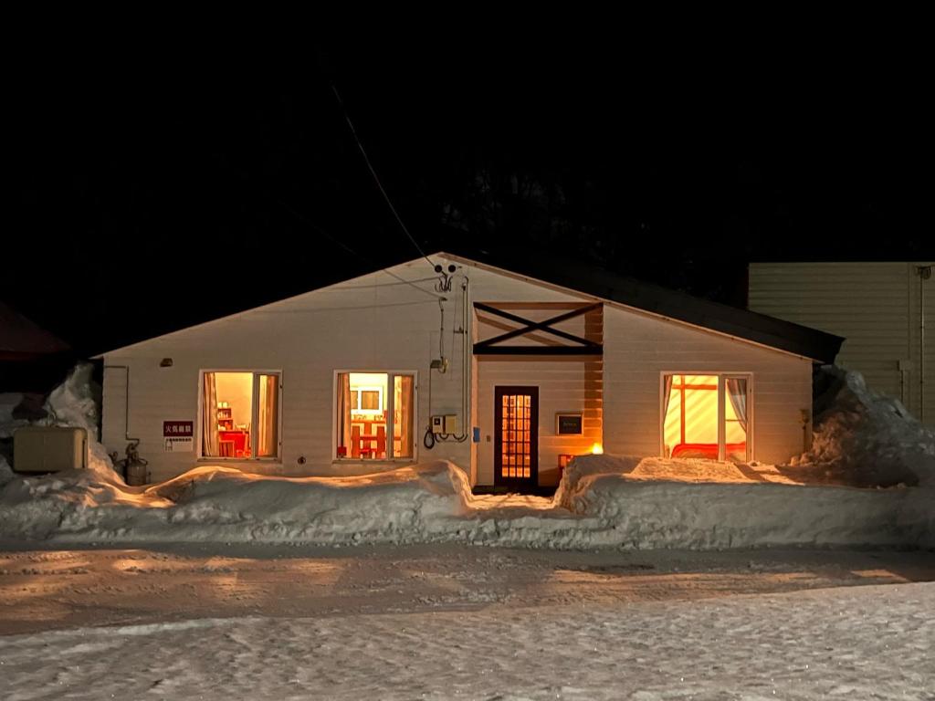 Una casa blanca con nieve alrededor por la noche en AnYa Ski in & Ski out at Pippu Hokkaido Max 6 ppl en Pippu