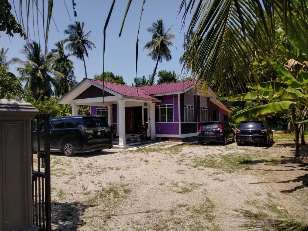 una casa púrpura con dos coches aparcados frente a ella en AR HOMESTAY & ROOMESTAY, en Merlimau
