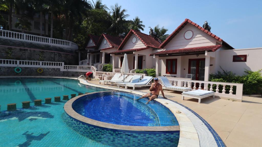 une femme est assise dans une piscine dans une maison dans l'établissement HỒNG BIN RESORT, à Duong Dong