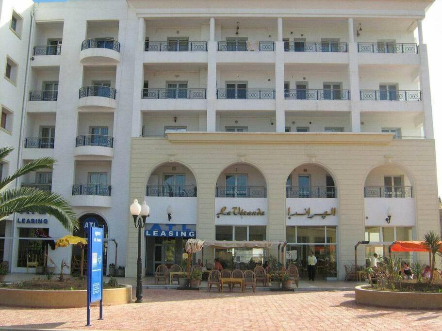 un gran edificio blanco con mesas y sillas delante de él en Appartement Slim centre sousse, en Sousse