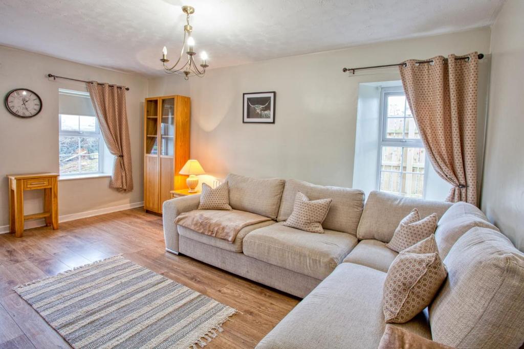a living room with a couch and two windows at Branch cottage in Limavady