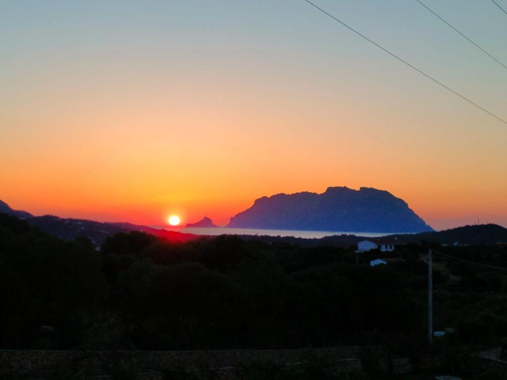 a sunset over the ocean with a mountain in the background at The Sunrise in San Teodoro