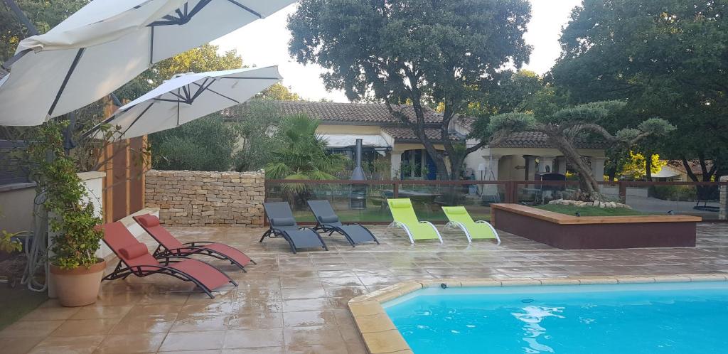 a group of chairs and umbrellas next to a pool at Les Gîtes de l'Arbousier in Quissac