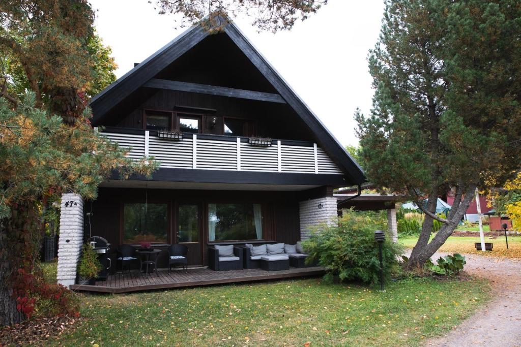 uma casa com um telhado preto com mesas e cadeiras em Villa Jupperi Espoossa em Espoo