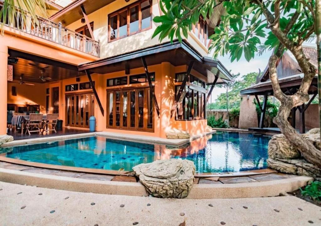 a swimming pool in front of a house at Villano Lilawadee Pool Villa in Na Jomtien