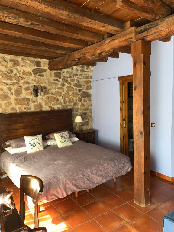 a bedroom with a bed and a stone wall at Hostal Rural Las Nubes in Salas de los Infantes