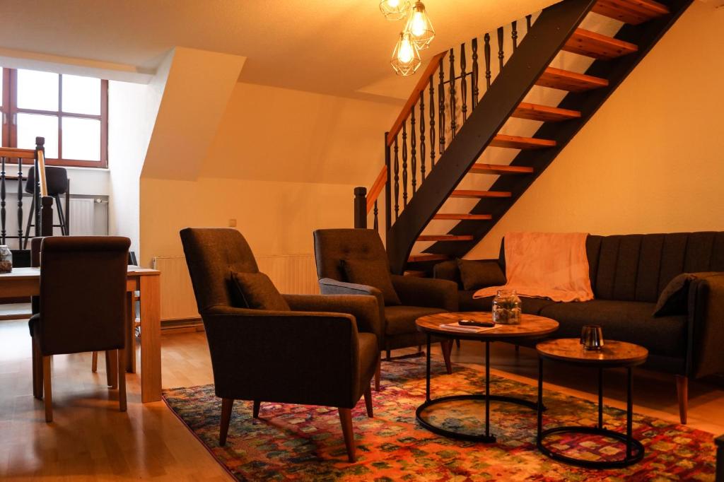 a living room with a couch and chairs and a staircase at Wohlfühlen in Lutherstadt Wittenberg inkl. Netflix in Lutherstadt Wittenberg