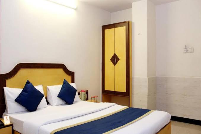 a bedroom with a large bed with blue pillows at Ganga Sagar Hotel in Bangalore