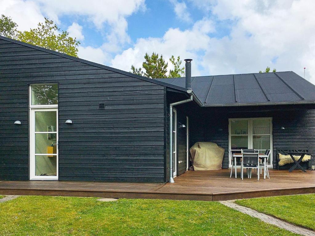 ein schwarzes Haus mit einer Holzterrasse mit einem Tisch in der Unterkunft Holiday home Thyholm XVII in Thyholm